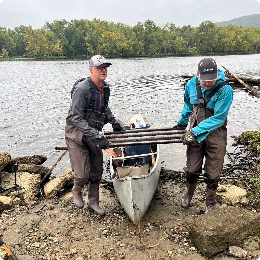 two men hauling large piece of trash from river